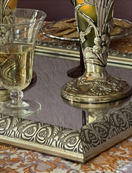 ornate bronze mirrored trav with flower vase and drinking glass